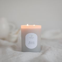 a lit candle sitting on top of a white bed sheet next to a teapot