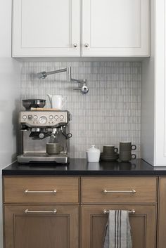 an espresso machine sitting on top of a counter next to white cupboards