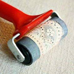 a red handled roller with lace on it