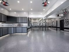 an empty garage with lots of grey cabinets and lights hanging from the ceiling, in front of a bike rack