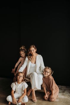 a woman sitting on the ground with two children in front of her and another child standing behind her