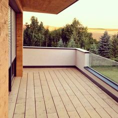 a balcony with wooden flooring and sliding glass doors on the side of it, overlooking trees