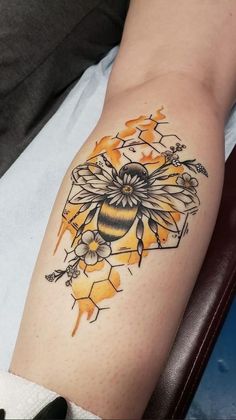 a tattoo on the arm of a woman with a bee and honeycombs design