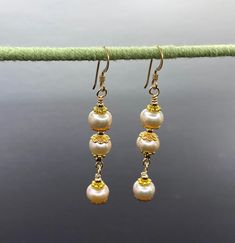 Unique presentation of peach freshwater pearls, antique gold spacers, and filigree bead caps in these elegant dangle earrings. The dangles are connected to each other and to the gold filled earwire through gold filled wrapped loops.  The earrings are about 1 1/4 inches long, measured from the earwire, and come nestled comfortably on a bed of cotton in a white cardboard box. Made in the USA by me. NA-821-0624-1111 Carmel Ca, Pearl Dangle Earrings, Pearl Earrings Dangle, Bead Caps, Cardboard Box, Antique Gold, Freshwater Pearls, Jewelry Earrings Dangle, Gold Filled