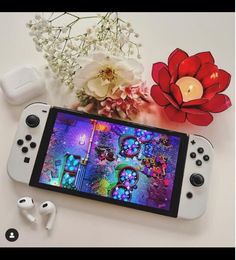 the nintendo wii game console is next to some flowers and an apple watch with ear buds