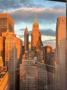 the city skyline is lit up at sunset with skyscrapers in the foreground and clouds in the background