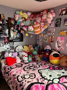 a bedroom with hello kitty bedding and lots of stuffed animals hanging from the ceiling