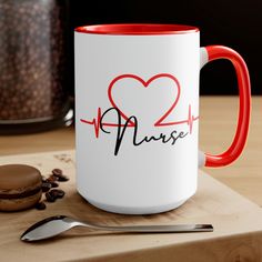 a red and white coffee mug sitting on top of a table next to a cookie