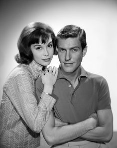 a black and white photo of a man and woman posing for the camera with their arms around each other