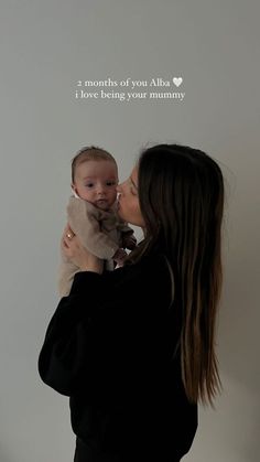 a woman holding a baby in her arms with a quote on the wall behind her