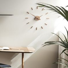 a wooden clock mounted to the side of a wall next to a table and chair