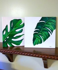 two paintings of green leaves on a shelf