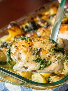 a person is spooning food out of a casserole dish with chicken and spinach