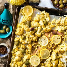 a tray filled with cauliflower and lemons next to olives