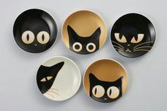 four black and white plates with cats painted on the front, one has yellow eyes