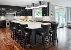 a large open concept kitchen and dining room with hardwood floors, black cabinets and white counter tops