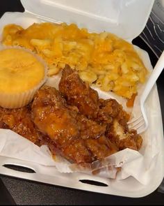 a plastic container filled with meat and macaroni and cheese next to a fork