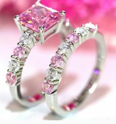 two wedding rings with pink and white diamonds on them, one is in the shape of a princess's ring