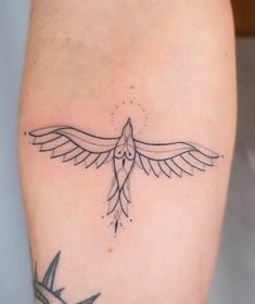 a small tattoo on the leg of a woman with a bird flying above her arm