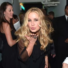 a woman blowing out her tongue at an event with other people in the back ground