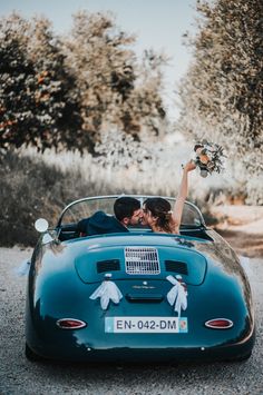 a bride and groom in an old fashioned sports car