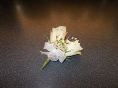 a boutonniere with white flowers on a black table