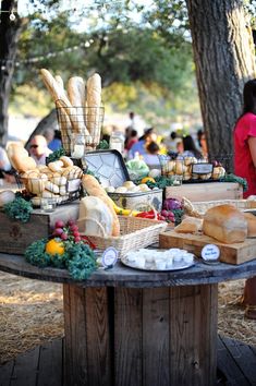 a table with breads and other food on it in the middle of a park