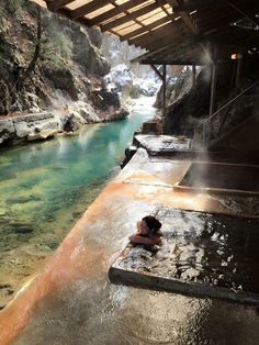 a person laying down in the water next to a hot springs with steam coming from it