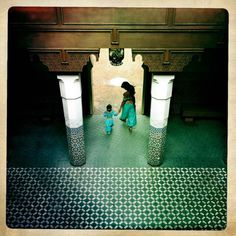 two people are walking through an open doorway in a building that has columns and pillars