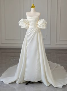 a white wedding dress on display in front of a mannequin's head