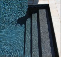 the shadow of a person standing in front of a swimming pool with steps leading up to it