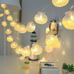 a table topped with lots of lights next to a white book and lamp shade on top of it