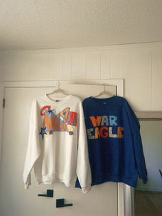 two sweatshirts hanging on a door hanger