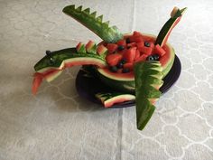 a watermelon fruit bowl with blueberries and other fruits in the shape of a dragon