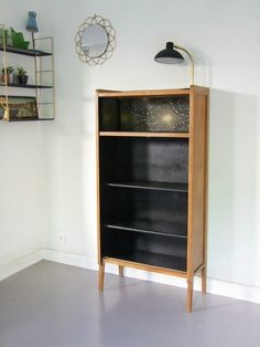 an empty room with a book shelf and lamp on the wall, next to a mirror