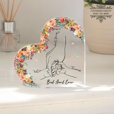 an acrylic heart shaped plaque with flowers on it