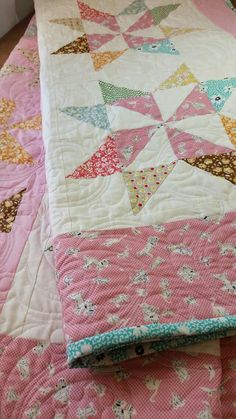 a pink and white quilt on top of a bed