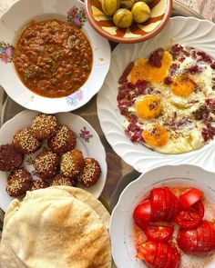 a table topped with lots of different types of food on white plates next to each other