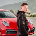 a man standing next to a red sports car in front of another red sports car