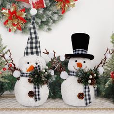 two snowmen with hats and scarfs are standing next to each other in front of christmas decorations