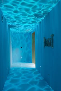 an empty hallway with blue walls and water on the floor is lit up by lights