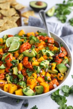 a white bowl filled with guacamole and other vegetables next to tortilla chips