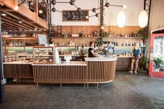 the interior of a coffee shop with people standing at the counter and behind it are hanging lights