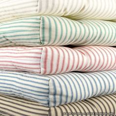 four striped pillows stacked on top of each other in different colors and sizes, all folded up