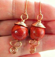 a pair of earrings with wire wrapped around the ends and red beads hanging from them