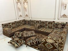 an ornately designed couch in the middle of a room with white walls and gold trimming