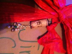 a wine bottle wrapped in red string and some beads on it's end with a tag attached to it