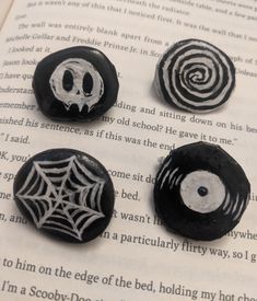 three black and white painted rocks sitting on top of an open book