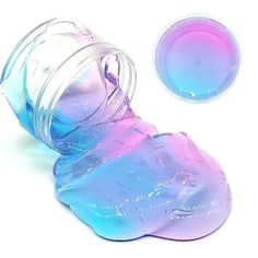 a glass jar filled with blue and pink liquid next to a plastic container on a white surface