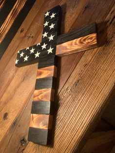 a wooden cross with an american flag painted on it sitting on top of a wood floor